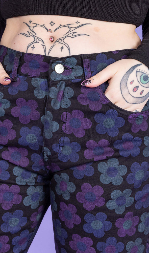 Close up of model's hand in pocket of DARK WASH 90's Black Magic Flower Wide Leg Stretch Jeans. The jeans are black with muted blue and purple flowers.
