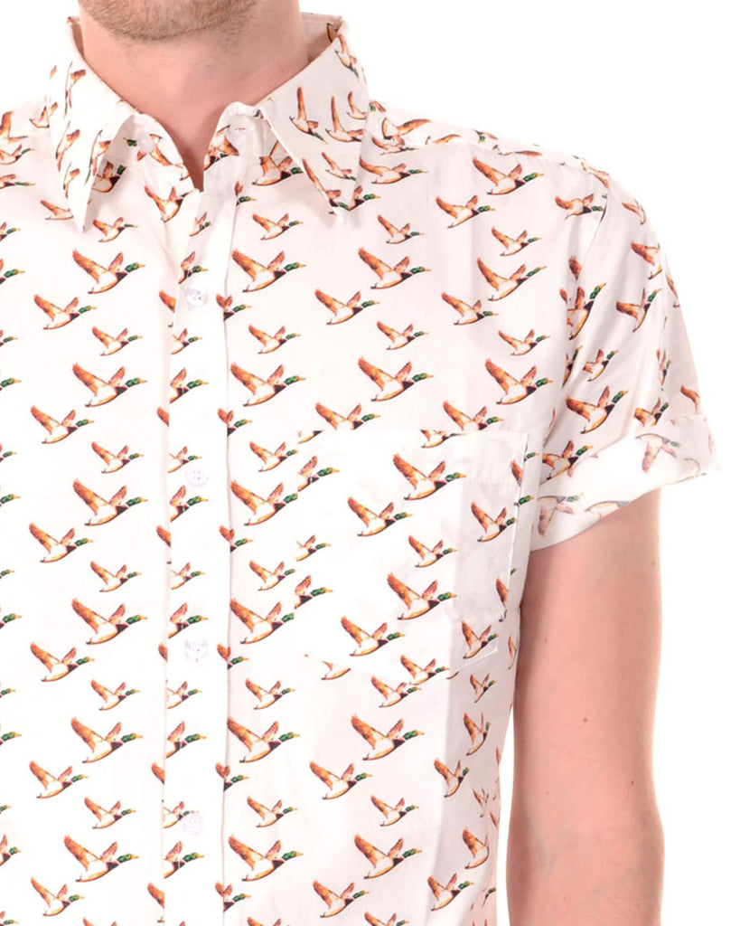 White flying ducks short sleeve shirt with orange ducks printed, retro style button up shirt with neck collar being modelled by a guy.