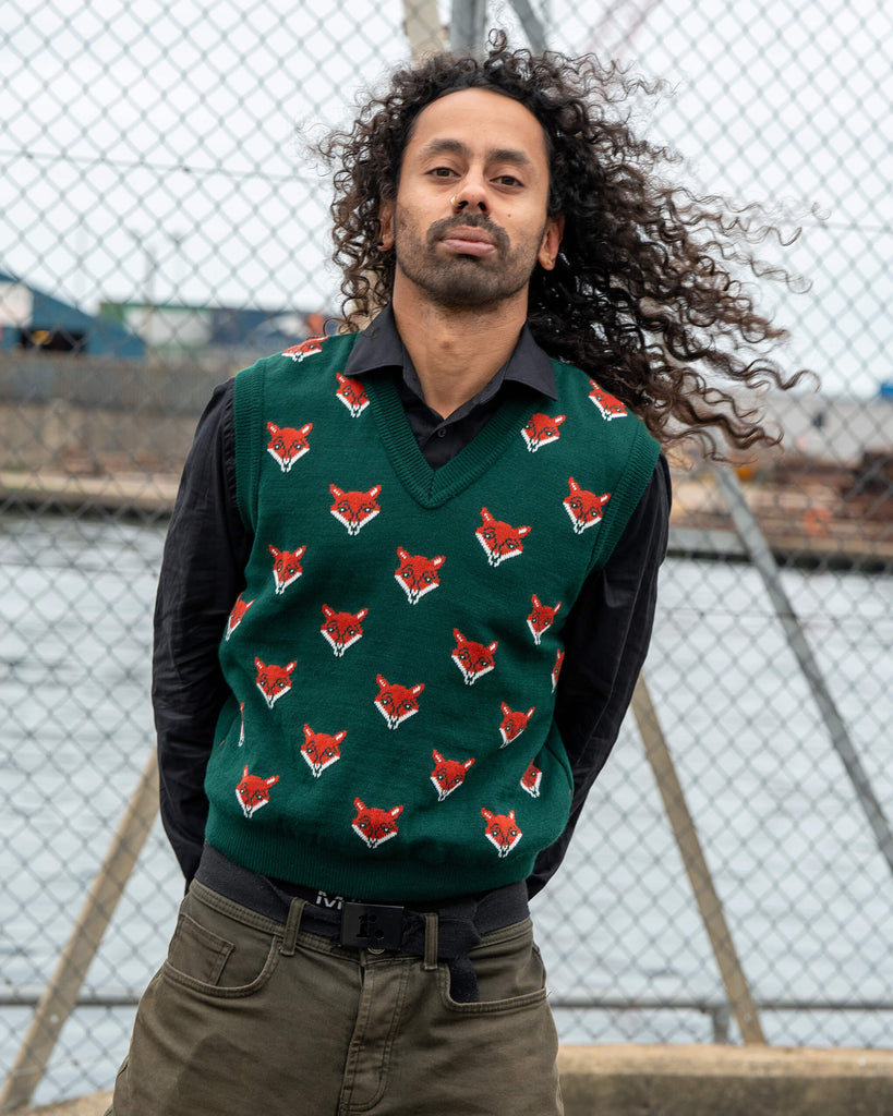 Front view of the unisex Run & Fly Fox Head Tank Vest with bright red fox face pattern on green. Model Rich wears it over a black shirt.