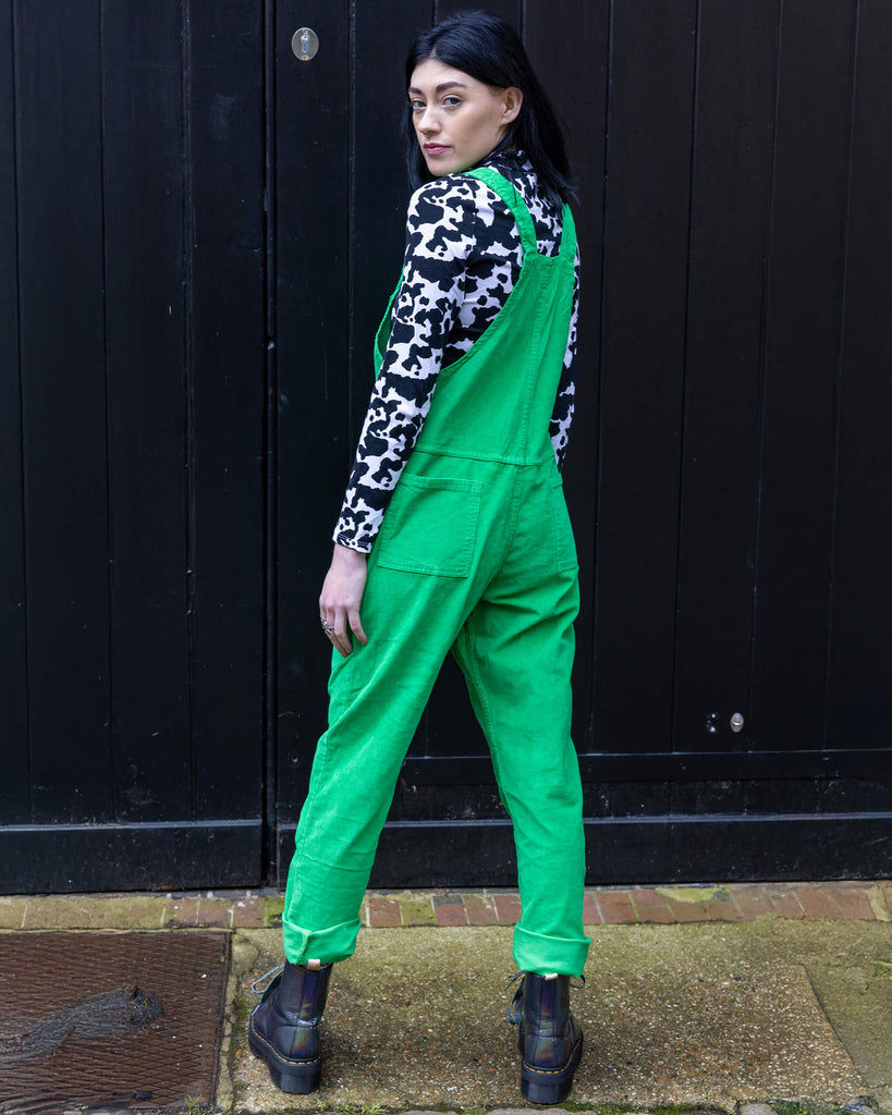 Gabriella a tall black haired model is wearing a green pair of corduroy dungarees with a cow print polo neck on underneath. She is against a purple background shot by Amy Davies Photography in Hove