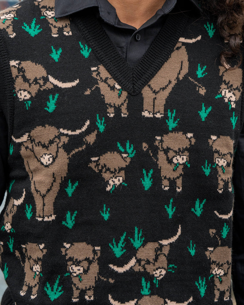 Close-up of the Run & Fly Highland Cow Tank Vest showing the detailed brown highland cow knit design with green grass on a black background. Made in England by Run & Fly.