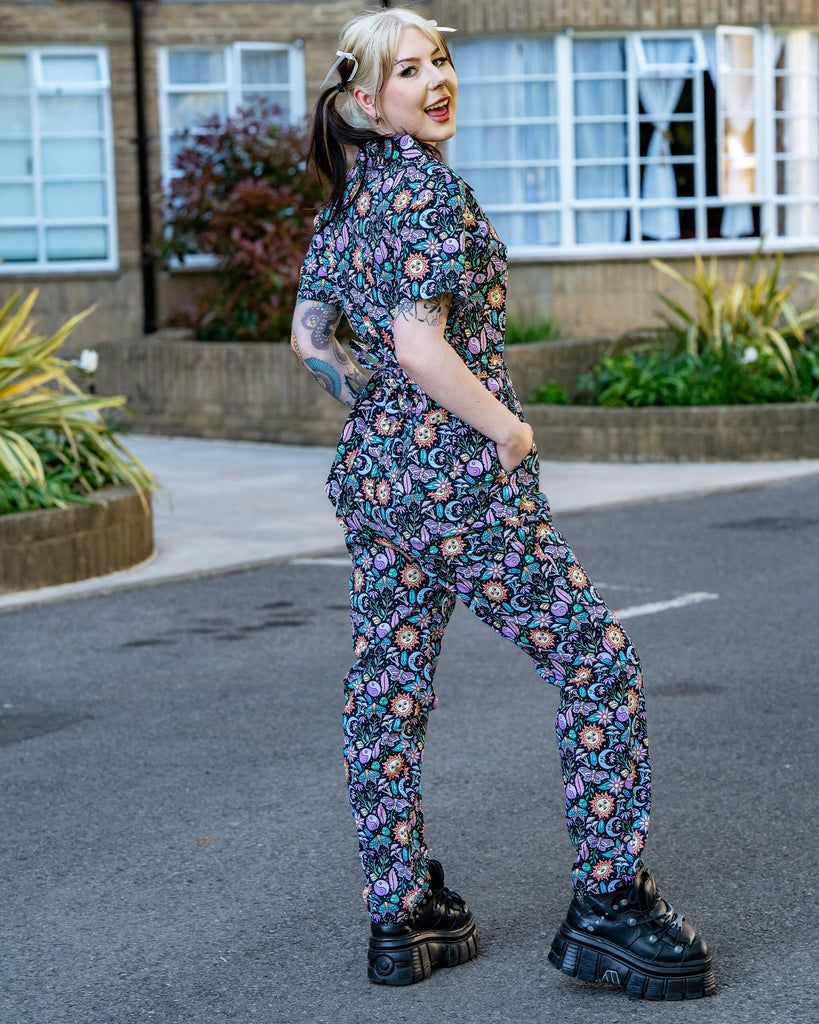 Back view of the Run & Fly Boho Summer Jumpsuit with hands in pockets, showcasing the stretchy fit and mystical all-over print. A bold and comfy ethical fashion piece.