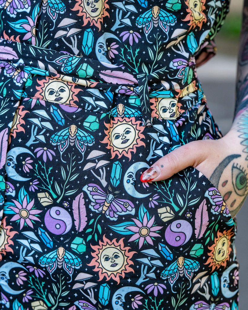 Close-up of the Boho Summer Stretch Jumpsuit by Run & Fly showing the side pocket and bold, magical print with pastel celestial and floral elements. Ethically made and full of personality.