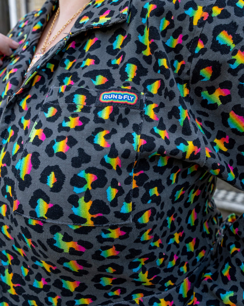 Close-up of the chest pocket on the Rainbow Leopard Stretch Twill Boiler Suit by Run & Fly. The pocket features the brand's logo, and the vibrant multicoloured leopard print stands out against the black background. This ethical slow fashion piece highlights bold, fun prints and high-quality design, perfect for expressing individuality.