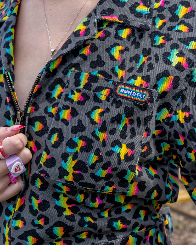 Detailed view of the front pocket of a black jumpsuit with a neon leopard print pattern. The pocket features the Run & Fly logo, highlighting the brand's attention to detail and quality. The vibrant colours and bold print make a striking statement in ethical fashion.