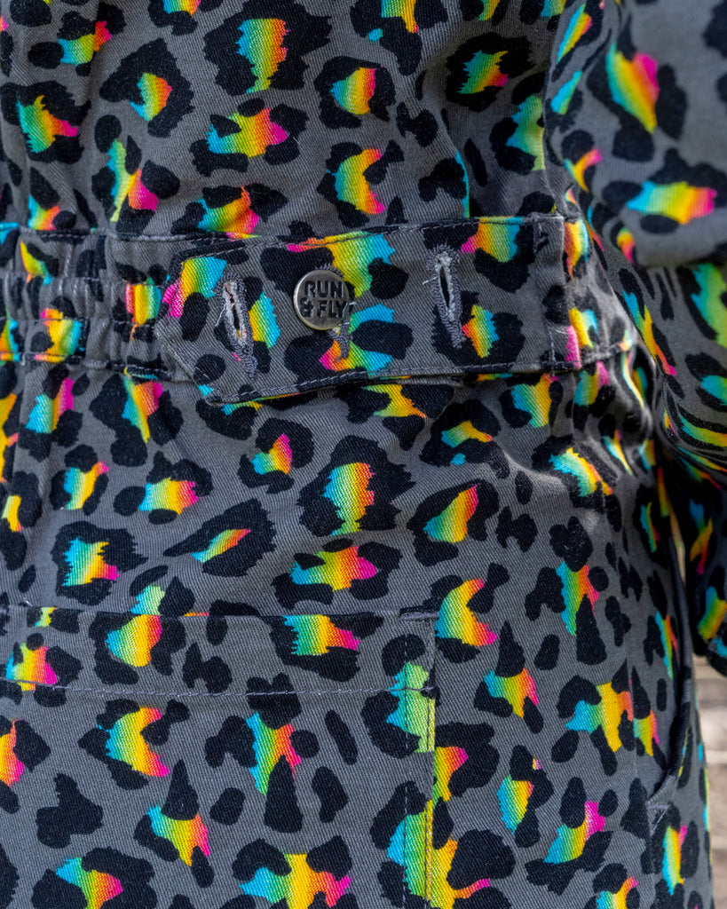 Close-up of the back pocket area of a black jumpsuit featuring a neon leopard print pattern. The image shows the Run & Fly branding and the high-quality stitching of the garment, emphasising the brand's commitment to ethical slow fashion and unique designs.