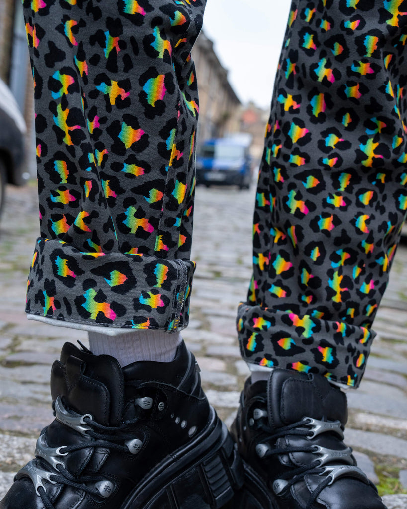 Close-up of the rolled-up hems of the Run & Fly Grey Rainbow Leopard Straight Leg Trousers, styled with white socks and chunky black platform shoes, showcasing the bold rainbow leopard pattern on grey fabric.