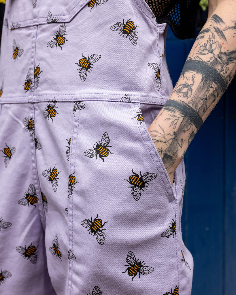 Closeup of Jamie wearing the Lavender bees stretch twill dungarees with is hand in the pocket.