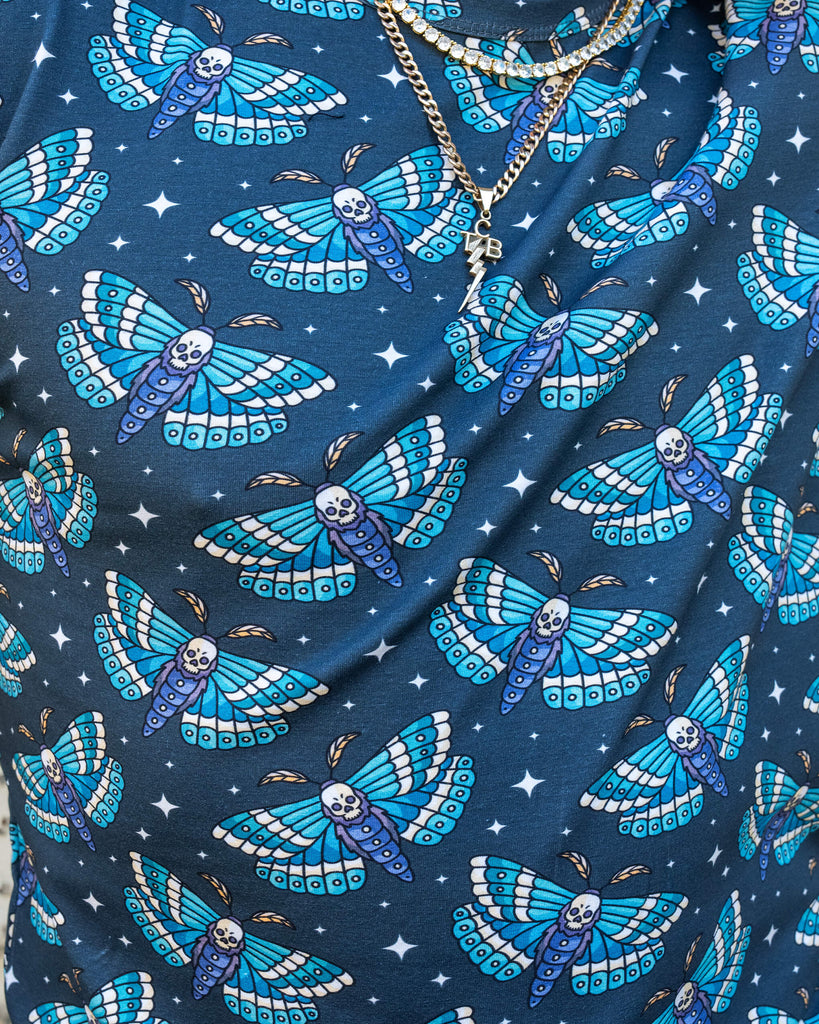 Close-up of the “Death Head Moth” print on Run & Fly’s t-shirt modelled by James. The design features blue and white moths with skull faces and stars, creating a striking, gothic-inspired aesthetic.
