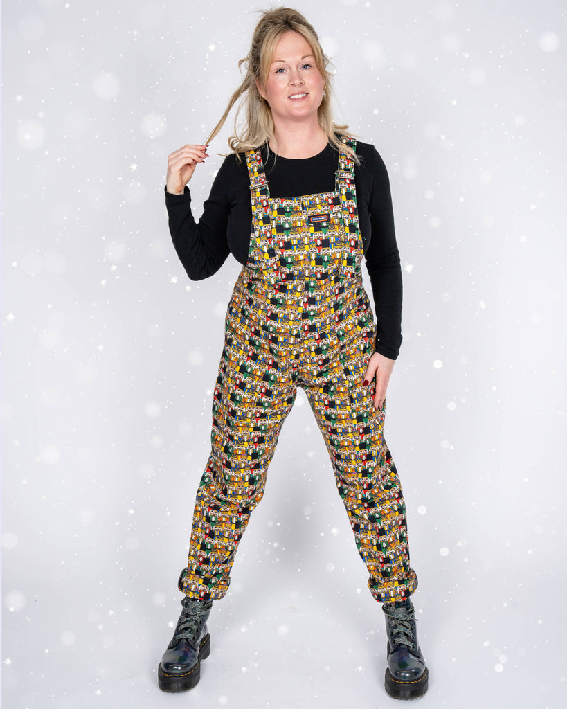 Karina strikes a confident pose with hands in her dungaree pockets. The Nutcracker print, featuring colourful festive characters, pops against her black top and the snowy background.
