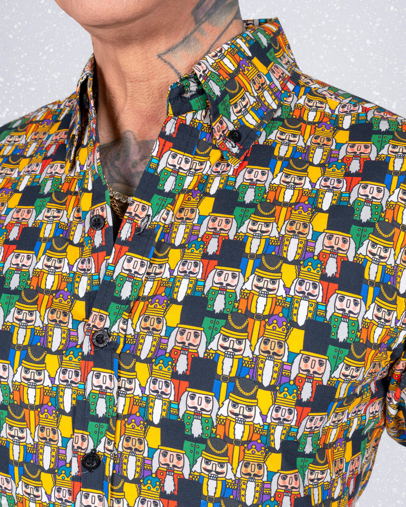 James showcases the front of the Nutcracker print shirt, highlighting its sharp collar and colourful design. The intricate Nutcracker characters stand out against the dark fabric, creating a festive and playful vibe.