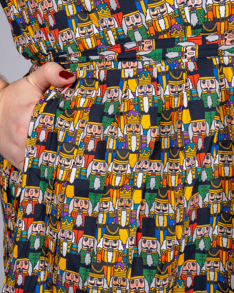 Close-up of dress pocket detail on Maddie’s Nutcracker print dress by Waffle Mama Design. The fabric showcases a variety of Nutcracker characters in festive colours, with Maddie’s hand in the pocket, showing off the dress’s practical style.