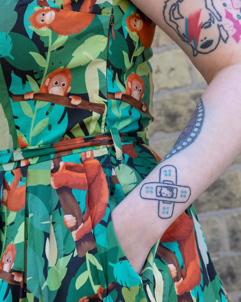 Faeryn's hand in the pocket of Orangutan Stretch Belted Tea Dress.