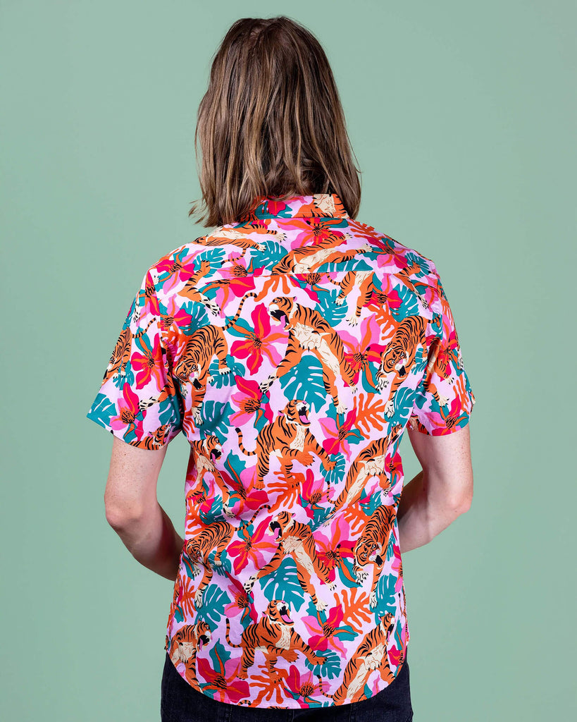 Jack is stood in a photography studio in Hove with a green backdrop wearing Tiger Lily Stretch Short Sleeve Shirt with jeans. The baby pink shirt has an all over print of tigers with flowers and leaves. Jack is stood with his back to the camera.