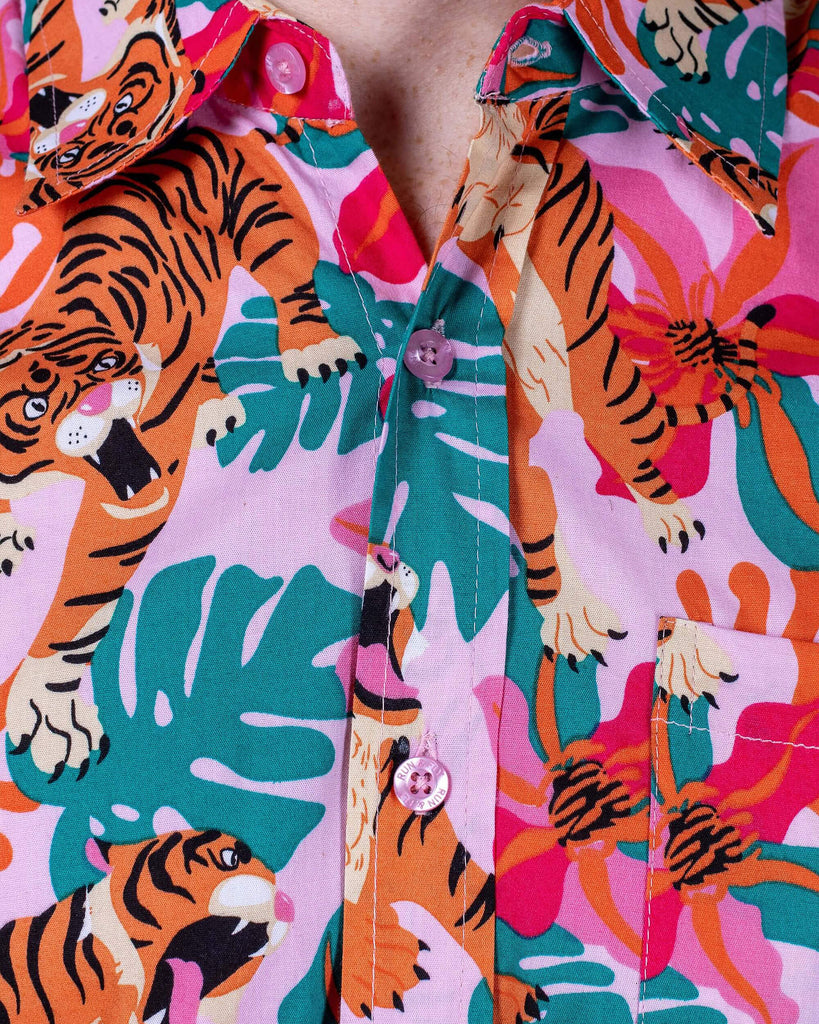 Close up of Jack wearing Tiger Lily Stretch Short Sleeve Shirt. Close up shows the all over print of tigers with flowers and leaves and the pink buttons on the shirt.