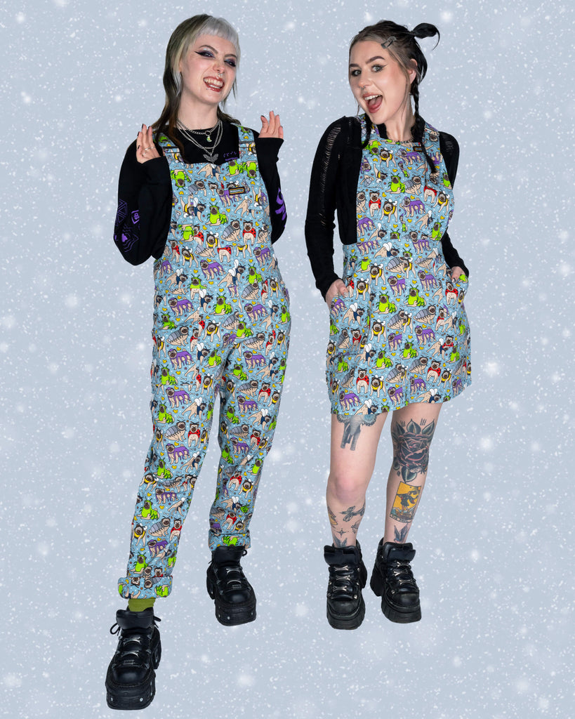 Faeryn poses with Flo wearing the matching ‘Pug Bugs’ dungaree pinafore by Run & Fly. Both showcase the playful pug-themed print in a quirky, fun pose, styled with black tops and chunky boots.