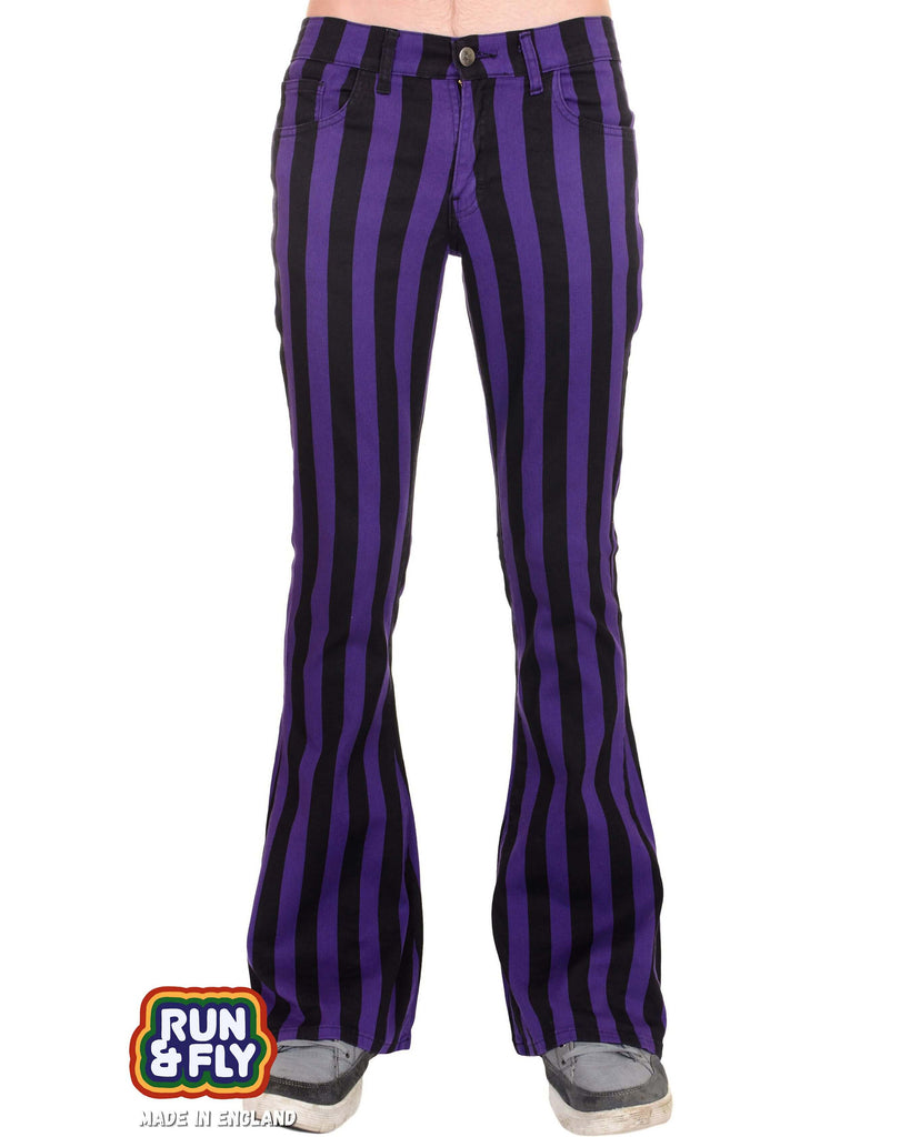 Model is stood in front of a white studio background wearing the purple and black striped bell bottom stretch super flares with grey trainers. They are facing forward and photo is cropped from the waist down.