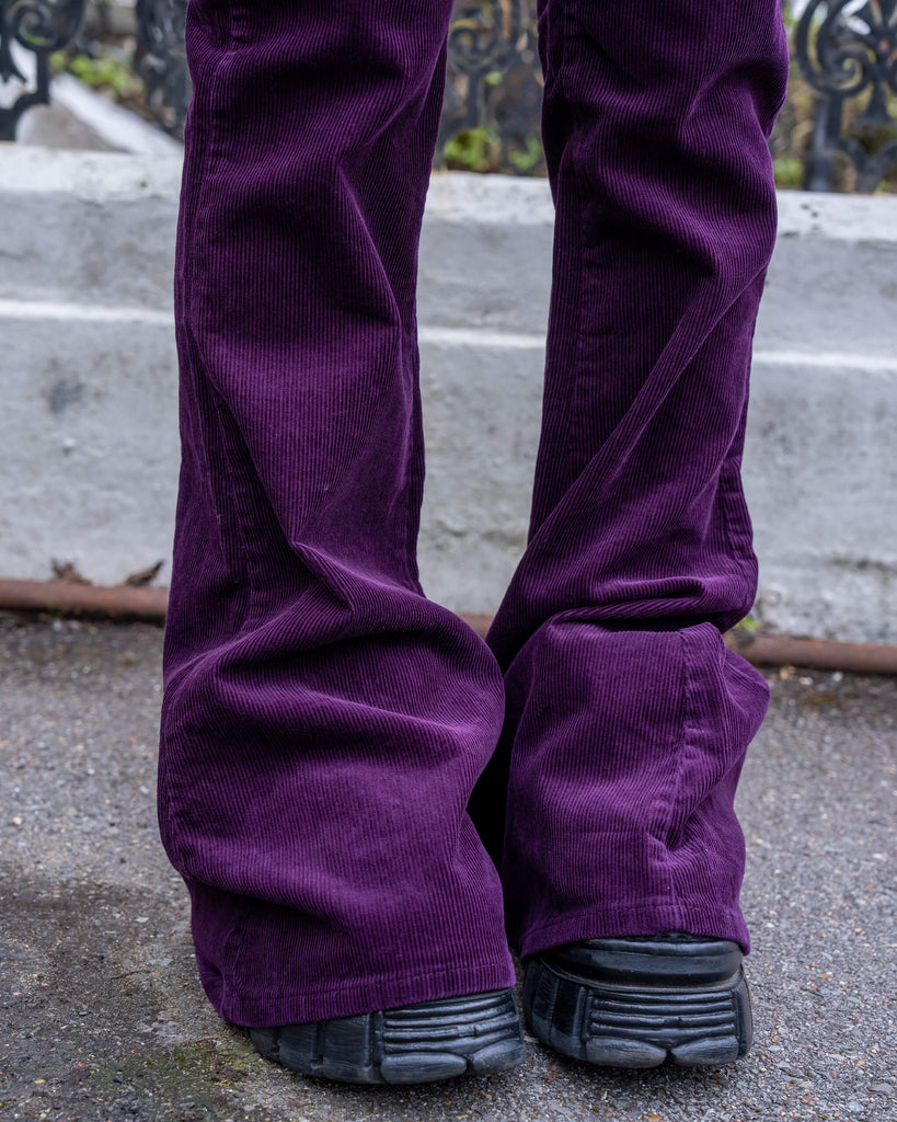 Hem close-up of the Run & Fly Midnight Purple Bell Bottom Flares over chunky black shoes, showing the wide flare and thick corduroy texture.
