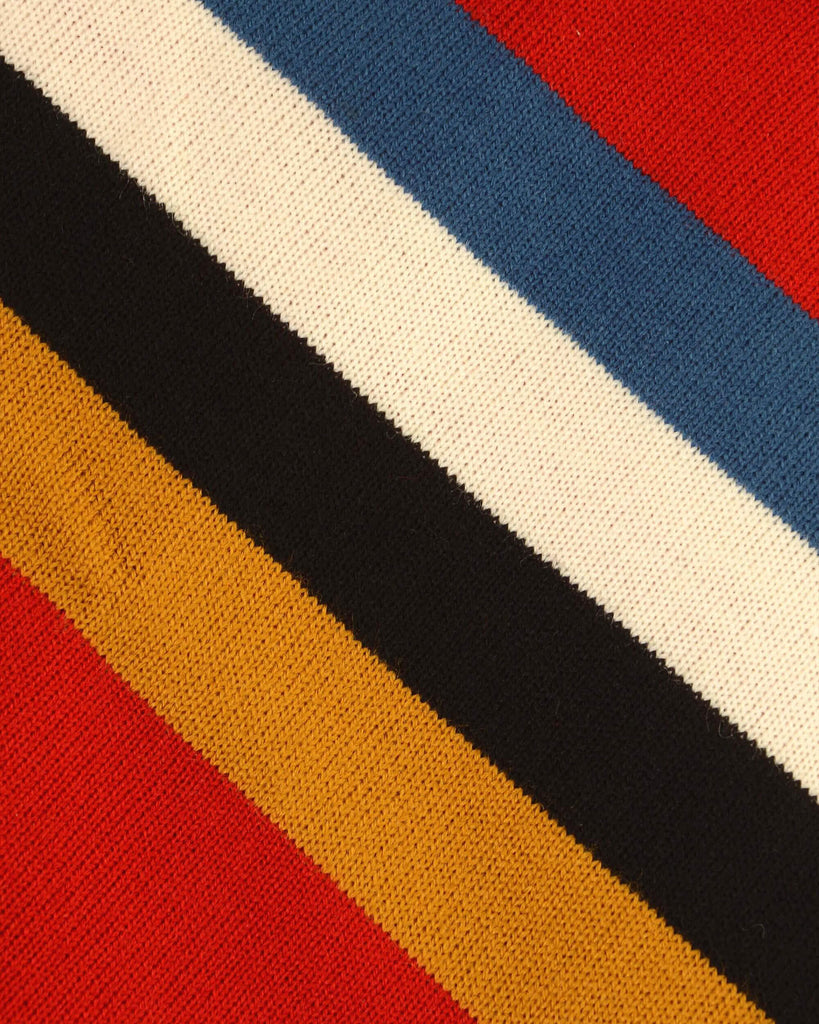 Close up showing off the blue, cream, black and mustard striped detail on the red retro zip neck jumper