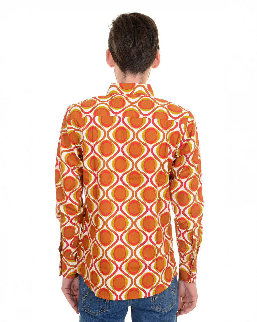 Model is stood in front of a white studio background wearing the retro mod geometric psychedelic printed 70s shirt with blue jeans. They are facing away posing with both arms resting by their side. Photo is cropped from the hips up.