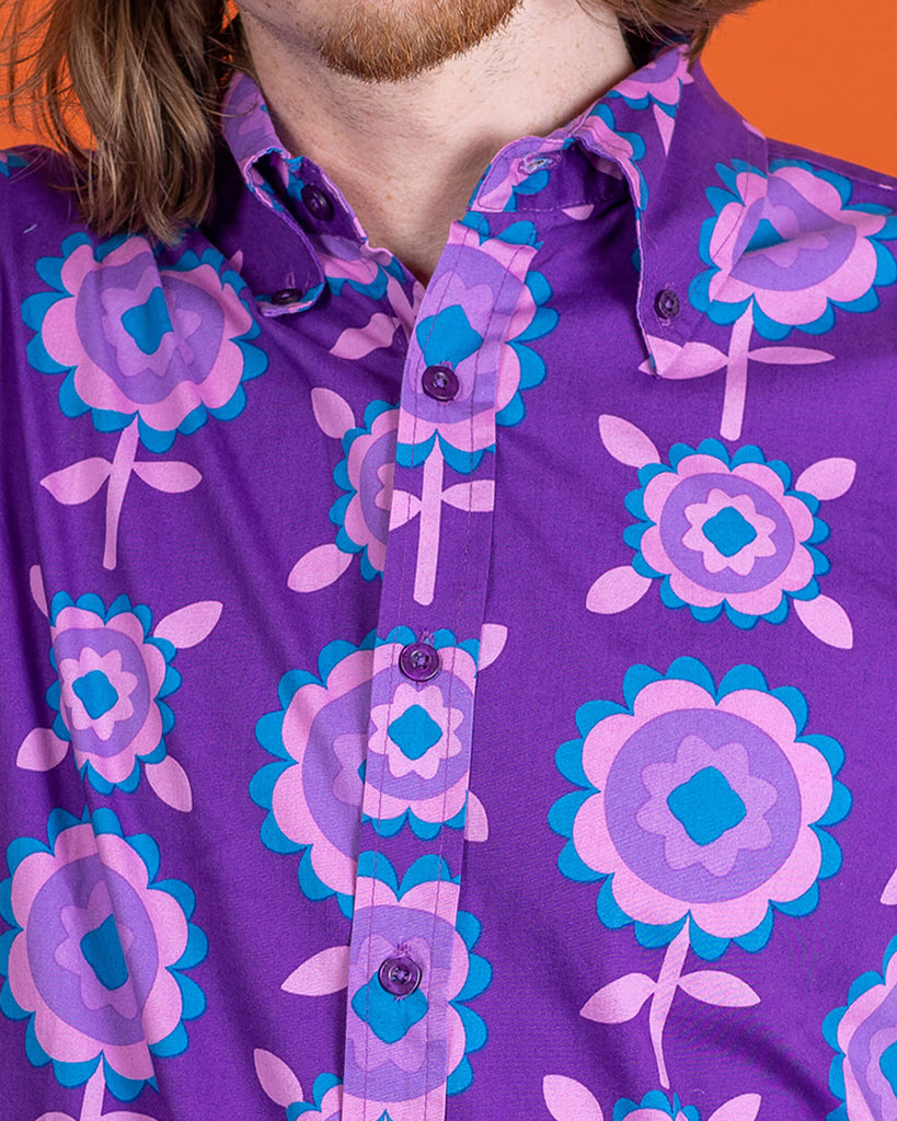 close up of Jack wearing Purple Retro Flowers Long Sleeve Shirt. Close up shows the retro flower pattern and purple buttons on the shirt.