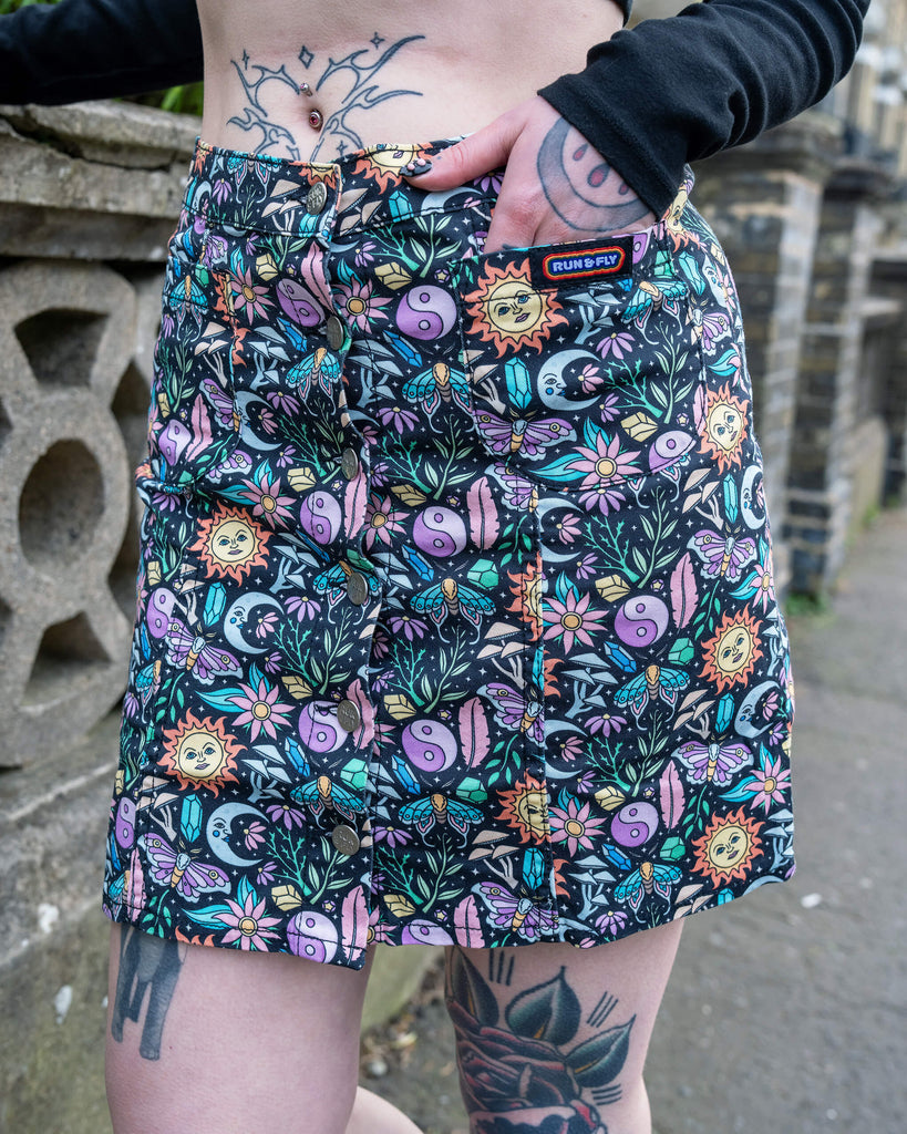 Front view of the Run & Fly Boho Summer A-Line Skirt showing the full vibrant mystical pattern and front button detail. The model has a belly piercing and tattoos.
