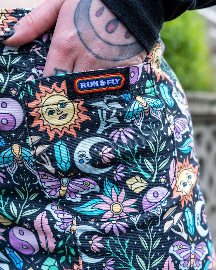 Detailed close-up of the Run & Fly Boho Summer A-Line Skirt showing the front pocket, pastel print, and rainbow Run & Fly label. A hand with tattoo and nail art rests inside the pocket.