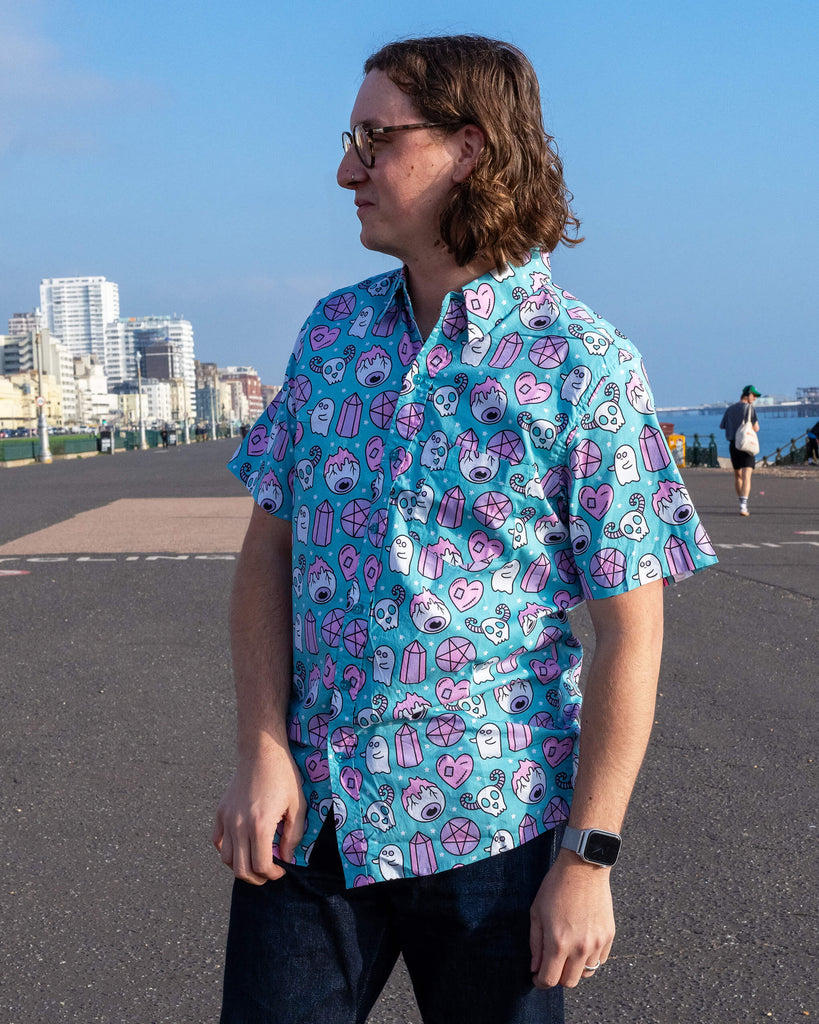 Side profile of the model wearing Run & Fly’s Spooky Stuff shirt. Features ethically crafted, colourful spooky motifs, including candy skulls, pentagrams, and hearts, combining fun with sustainable fashion.
