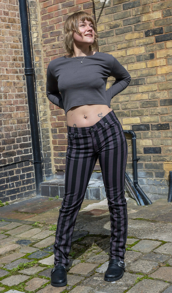 Model Julia is in her 20's with short blonde hair and is facing forwards wearing grey and black vertically striped skinny jeans