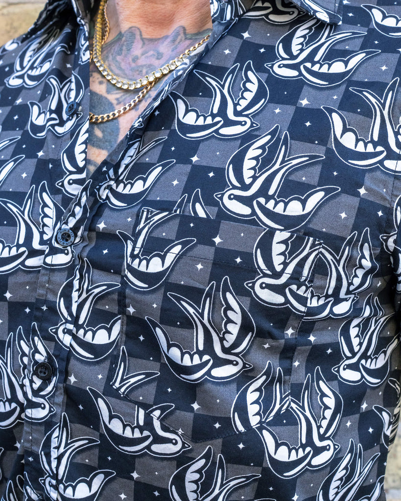 Close-up of the Run & Fly swallow print shirt, highlighting the black and white bird pattern with tiny star details. The soft, breathable fabric has a slight sheen, and the classic collar and button-up front add a smart-casual touch. Run & Fly creates ethical slow fashion with vibrant prints.