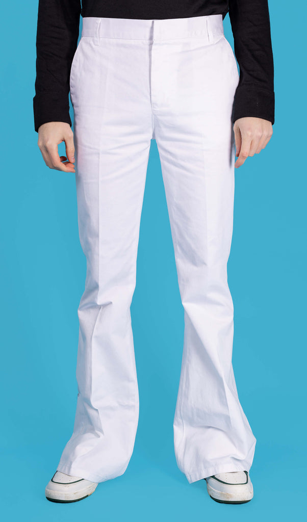 Jack is stood in front of a blue studio background wearing the Presley white cotton bell bottom trouser slacks with a long sleeve black tshirt and white trainers. They are facing forward posing with both hands resting by their sides. Photo is cropped from the waist down.