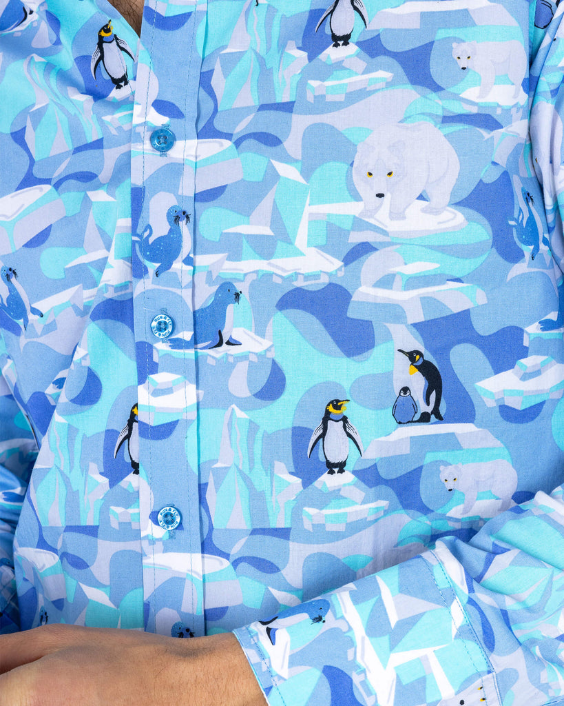 close up of Rudi wearing Run & Fly Winter Friends Long Sleeve Shirt paired with grey trousers. The shirt is ight blue colour with ice burgs, seals, polar bears and penguins on. The close up shows the pattern in more detail.
