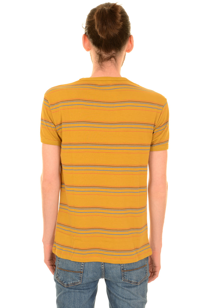 Model is standing in front of a white studio background wearing the sunset stripe retro tshirt with blue jeans. They are facing away from the camera with both arms resting by their sides. Photo is cropped from the hips up.