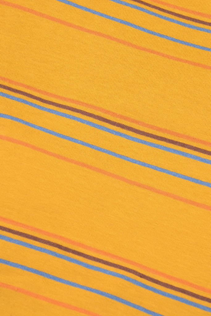 Close up of the sunset stripe retro tshirt fabric which is a mustard yellow base colour with blue, brown and orange stripes running through it.