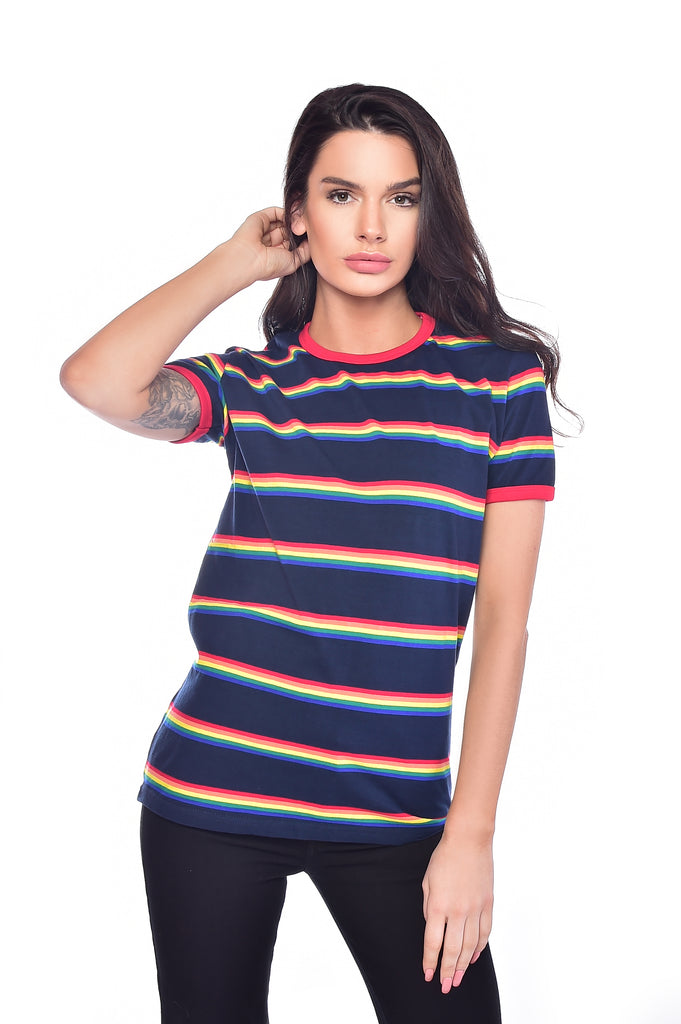 Model standing in front of a white background with long dark hair and wearing the retro rainbow block striped tee