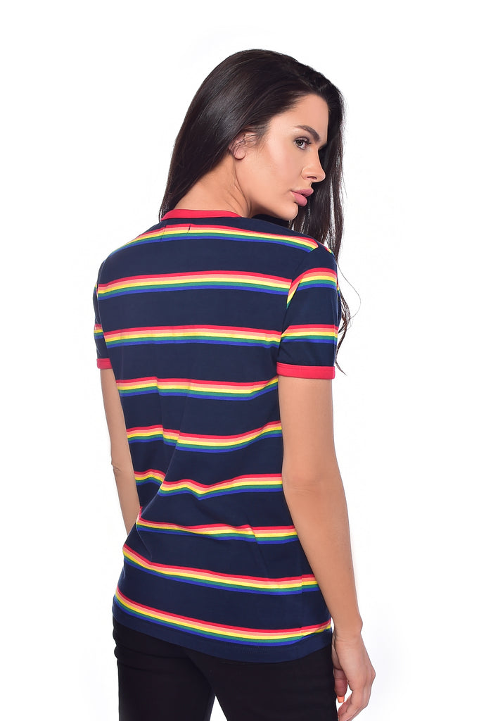 Model standing  away from the camera, in front of a white background with long dark hair and wearing the retro rain bow block striped tee