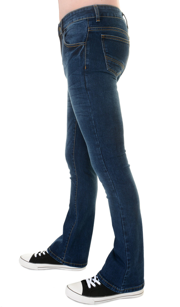 Model is stood in front of a white studio background wearing the distress stonewash stretch denim slim bootcut jeans with black converse trainers. They are facing towards the left and photo is cropped from the waist down.