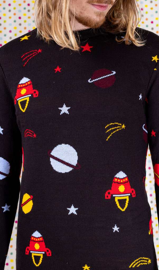 Close up photo of the front of the retro rocket outer space jumper modelled by Jack in front of a multicoloured polka dot background.